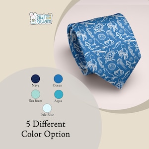 Puede incluir: Una corbata azul con un estampado blanco de vida marina, que incluye tortugas, caballitos de mar y medusas. La corbata está doblada y se muestra sobre un fondo neutro. La imagen también muestra cinco opciones de color: azul marino, océano, espuma de mar, aguamarina y azul pálido.