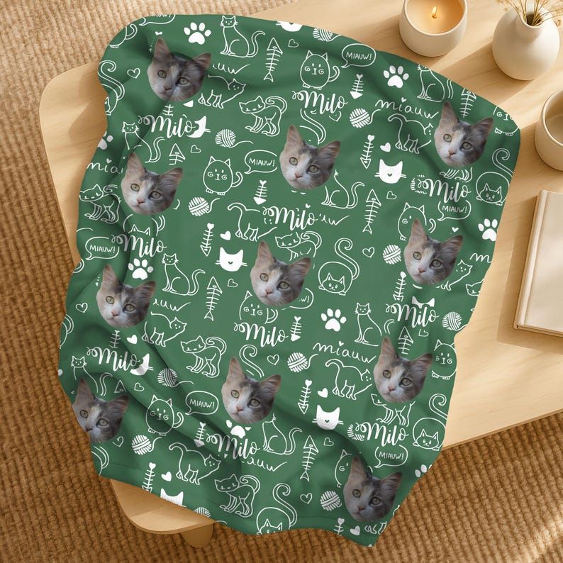 May include: A green blanket featuring a repeating pattern of white line-art cat silhouettes, fish bones, yarn balls, paw prints, and the text "Milo" and "miauw". Interspersed among the graphics are realistic photographic portraits of a cat.