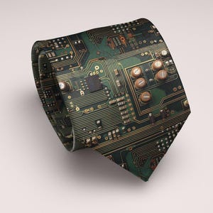 May include: A rolled-up necktie featuring a detailed circuit board design. The tie is predominantly dark green with gold and copper-colored accents, showcasing a complex pattern of electronic components.