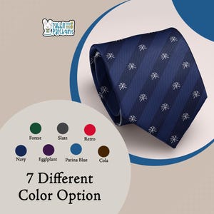 May include: A navy blue necktie featuring alternating dark and light blue diagonal stripes with a repeating white Chi Rho symbol pattern. The image includes a logo with a rabbit and the text Rabbit Patch Gifts, plus a color chart with seven options.