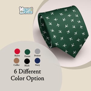 Peut inclure: Une cravate vert forêt avec un motif répété d'avions blancs. La cravate est pliée, mettant en valeur son design. L'image affiche également six options de couleurs : rouge, vert, gris, marron, noir et bleu marine. Le texte indique "6 Different Color Option."