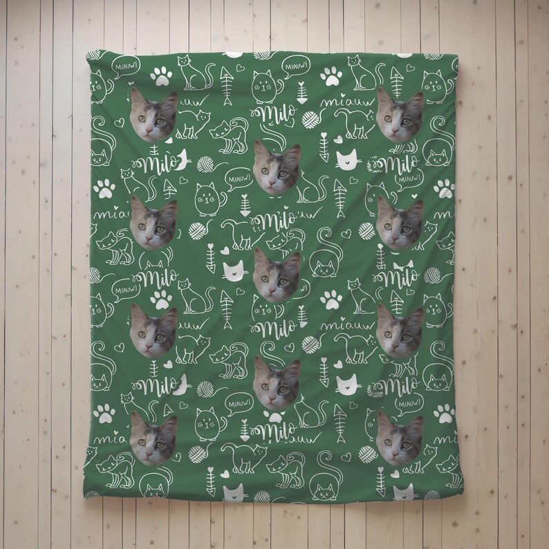 May include: A green blanket featuring a repeating pattern of white line drawings of cats, fish bones, yarn balls, and paw prints. The design includes the name Milo in a script font and the word miauw, interspersed with photos of a cat.