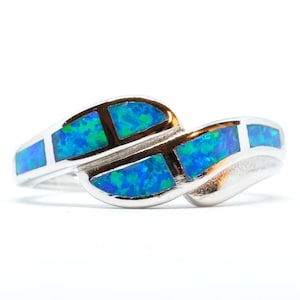 May include: A silver ring with a swirling design, featuring rectangular blue and green opal inlays. The ring has a polished finish and is set against a white background, showcasing the vibrant colors of the gemstones.