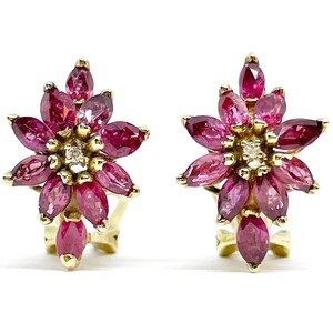Op de afbeelding: Een paar goudkleurige oorbellen, elk met een bloemmotief. De oorbellen zijn versierd met marquise-geslepen, dieproze edelstenen en een kleine diamant in het midden. De edelstenen zijn gerangschikt als bloemblaadjes.