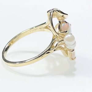 Pu&ograve; includere: Un anello d'oro con un gruppo di perle bianche e una pietra di opale. L'anello &egrave; incastonato in un design delicato e intricato.