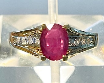 May include: A gold ring featuring a large oval ruby gemstone surrounded by smaller diamonds.