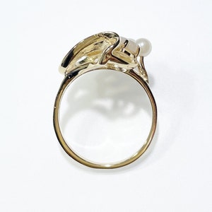 Pu&ograve; includere: Un anello d'oro con un designo astratto unico con un solo accento di perla.