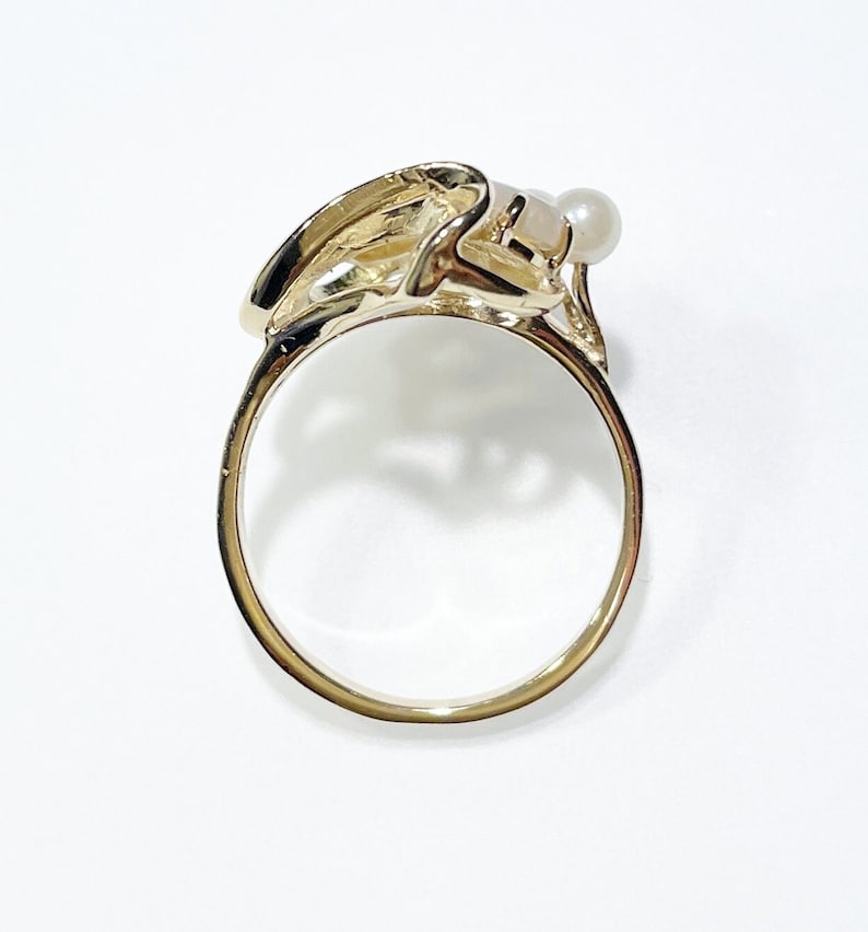 Pu&ograve; includere: Un anello d'oro con un designo astratto unico con un solo accento di perla.