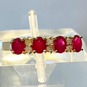 May include: A gold band ring with five oval-shaped red gemstones and smaller white gemstones set in between.