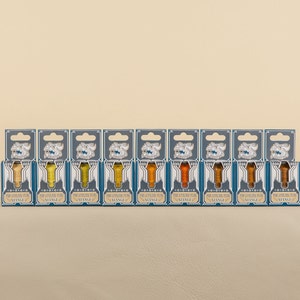 May include: Ten small bottles of ink in various shades of yellow and orange. Each bottle is labeled "The Fountain Pen Ink Co.  " and "VINTAGE".