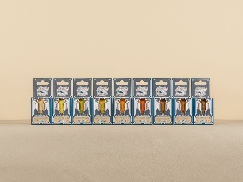 May include: Ten small bottles of ink in various shades of yellow and orange. Each bottle is labeled "The Fountain Pen Ink Co.  " and "VINTAGE".