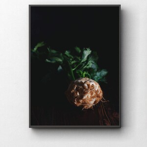 Könnte beinhalten: Nahaufnahme einer Sellerieknolle mit ihren grünen, blättrigen Stielen auf einer dunklen Holzoberfläche.