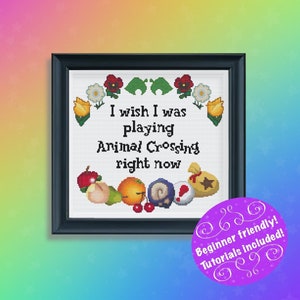 Puede incluir: Obra de punto de cruz enmarcada en negro con el texto "I wish I was playing Animal Crossing right now." El diseño incluye iconos relacionados con el juego y elementos florales. Un círculo morado con texto en la esquina inferior derecha.
