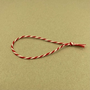 May include: A red and white twisted string with a knot at one end.