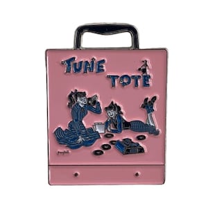 Può includere: Borsa a mano in metallo rosa con manico e design retrò. La borsa a mano presenta il testo "Tune Tote" e un'illustrazione di due donne che ascoltano dischi.