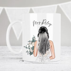 May include: White ceramic mug with a black and white illustration of a bride wearing a white veil and holding a bouquet of white flowers. The text "Mrs. Riley" is printed on the mug.