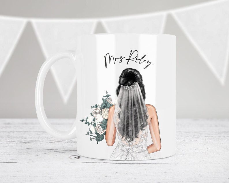 May include: White ceramic mug with a black and white illustration of a bride wearing a white veil and holding a bouquet of white flowers. The text "Mrs. Riley" is printed on the mug.