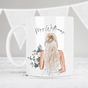 May include: White ceramic mug with a bride illustration holding a bouquet of white flowers and greenery. The text "Mrs. Williams" is printed on the mug.