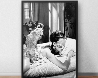 May include: A black and white photograph of a woman wearing a sleep mask lying in bed with a cat sitting on the bed behind her.