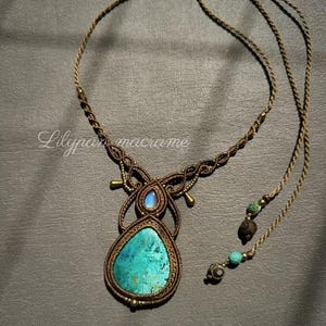 Puede incluir: Collar de macramé hecho a mano con un colgante de piedra turquesa en forma de lágrima. El colgante está envuelto en un cordón marrón tejido, con una piedra azul más pequeña y detalles dorados. El collar tiene un cordón largo y ajustable.
