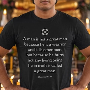 May include: A black short-sleeved t-shirt featuring a white circular emblem and the text: A man is not a great man because he is a warrior and kills other men; but because he hurts not any living being he in truth is called a great man. Dhammapada, 405.