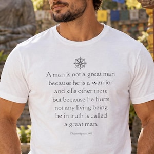 May include: A white short-sleeved t-shirt featuring a black graphic of a dharma wheel and the text: A man is not a great man because he is a warrior and kills other men; but because he hurts not any living being he in truth is called a great man. Dhammapada, 405.