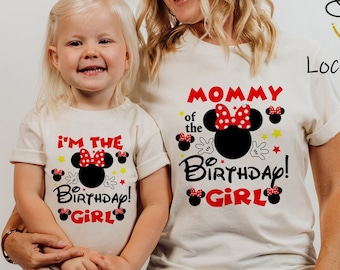 Può includere: Una maglietta bianca con il testo "Mommy of the Birthday Girl!" e un'immagine di Minnie Mouse in nero e rosso. Una seconda maglietta bianca con il testo "I'm the Birthday Girl!" e un'immagine di Minnie Mouse in nero e rosso.