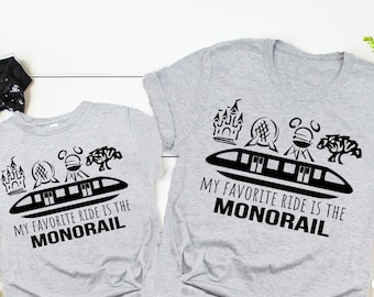May include: Two grey t-shirts with black text and graphics. The shirts say "My favourite ride is the monorail" and feature a monorail, castle, and other Disney icons.
