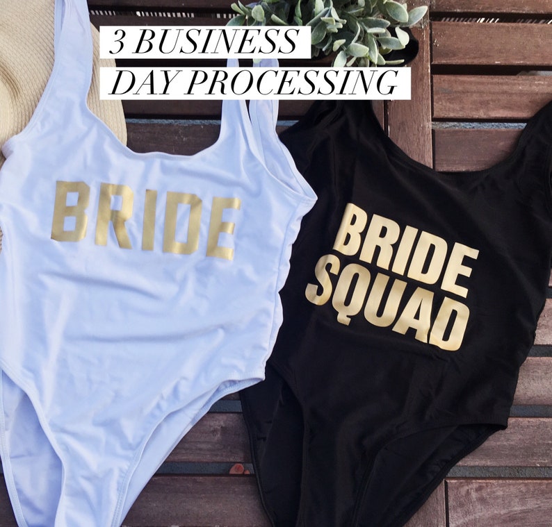 May include: Two one-piece swimsuits, one white and one black, with gold lettering. The white swimsuit says "BRIDE" and the black swimsuit says "BRIDE SQUAD". The image also includes the text "3 BUSINESS DAY PROCESSING".