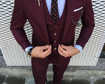 May include: A burgundy three-piece suit with a white shirt and a patterned tie. The suit has a vest and a pocket square.