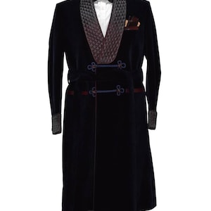 May include: A navy blue velvet robe with a black quilted shawl collar and a matching sash. The robe has a decorative knot detail on the sash and a tassel at the bottom.