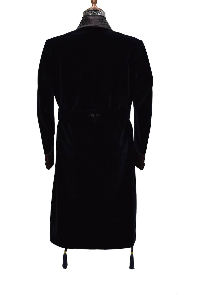 May include: A black velvet robe with a quilted collar and a matching belt. The robe has long sleeves and a tassel at the bottom of each side.