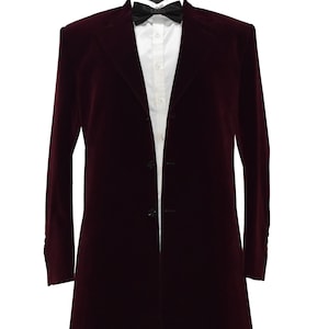 Peut inclure: Un blazer long en velours bordeaux avec un nœud papillon noir et une chemise blanche. Le blazer a une fermeture à bouton unique et un revers en pointe.