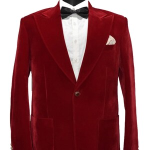 May include: A red velvet blazer with a single button closure and a pocket on each side. The blazer has a shawl collar and is displayed on a mannequin wearing a white shirt and a black bow tie.