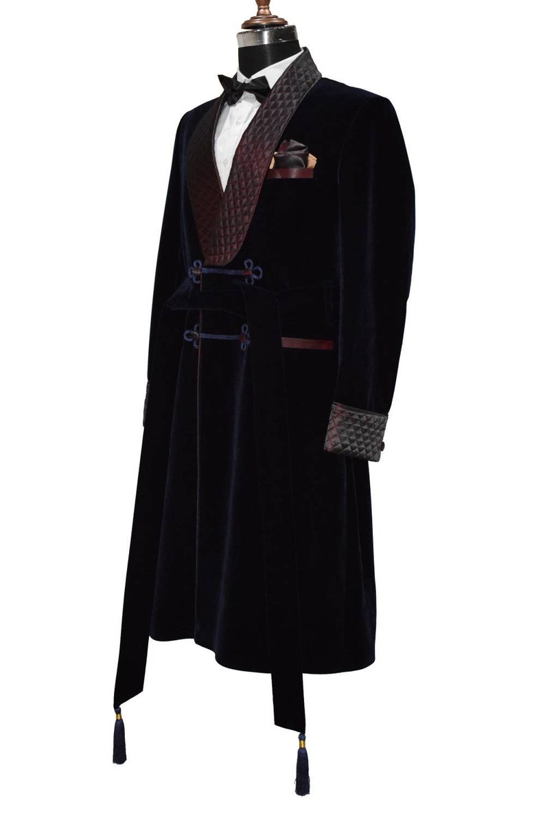 May include: A long, dark blue velvet robe with a burgundy velvet shawl collar and a black bow tie. The robe has a sash with gold buckles and tassels.