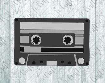 May include: A black and gray cassette tape with a white label. The tape is on a white wooden background.