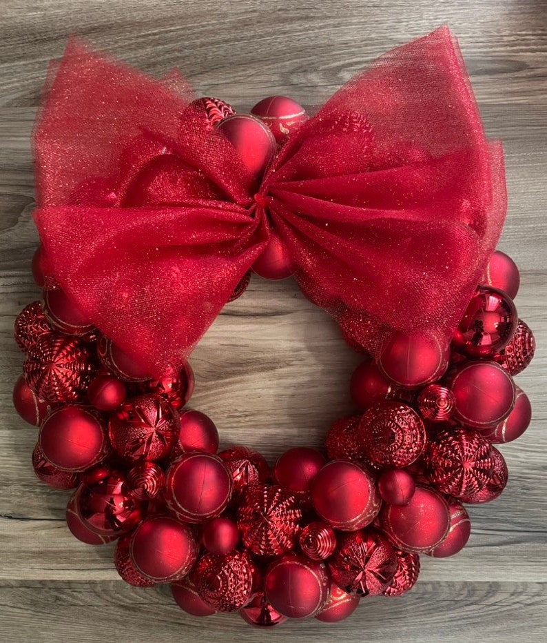 K&ouml;nnte beinhalten: Ein roter Weihnachtskranz aus roten Kugeln und einer roten T&uuml;llschleife.