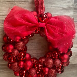 K&ouml;nnte beinhalten: Ein roter Weihnachtskranz aus roten Kugeln und einer roten T&uuml;llschleife.