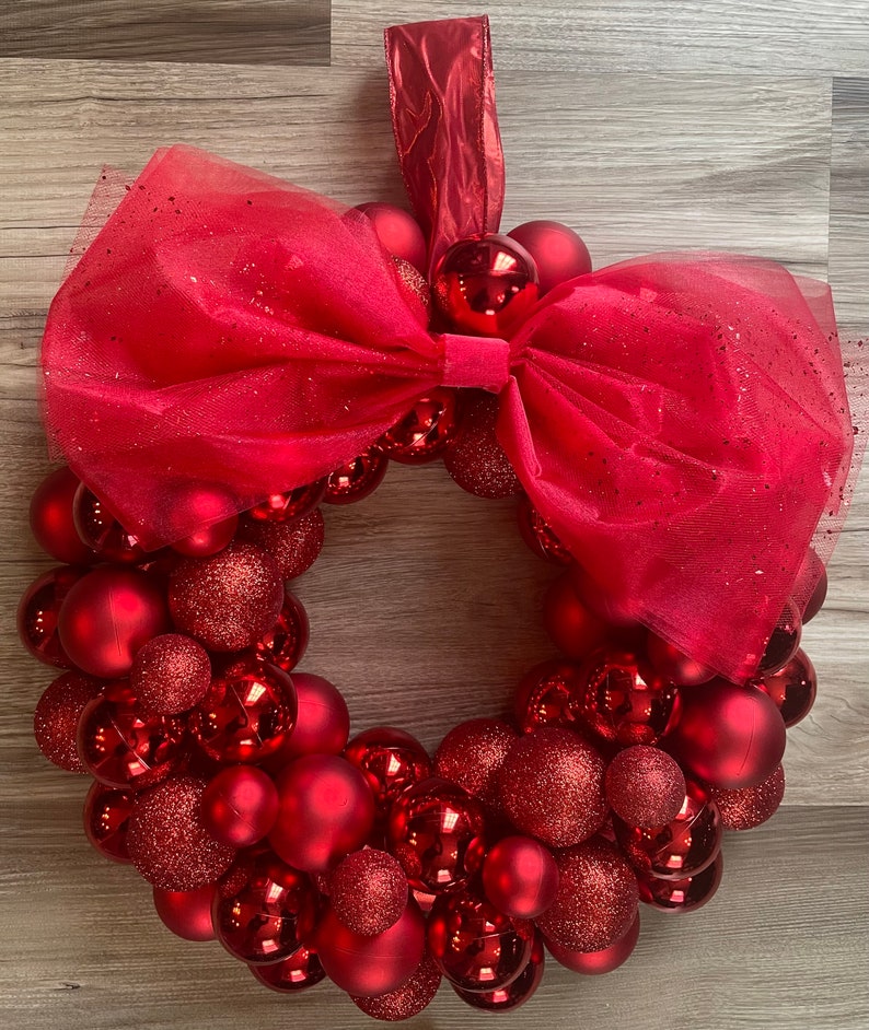 K&ouml;nnte beinhalten: Ein roter Weihnachtskranz aus roten Kugeln und einer roten T&uuml;llschleife.
