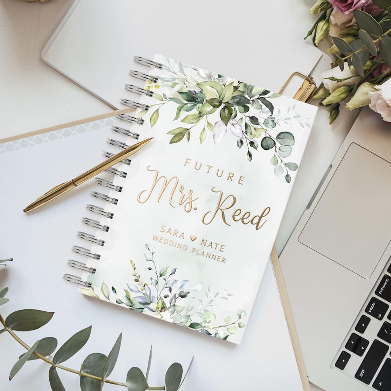 Personalized floral wedding planner book with gold foil text. Features elegant greenery artwork. Ideal for organizing wedding plans, budgeting, and checklists. A thoughtful bridal shower gift, engagement present, or keepsake for a bride-to-be.