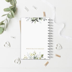 May include: A white spiral bound journal with a watercolor floral design on the front and back covers. The front cover has the text "#BESTDAYEVER2020" in gold lettering.