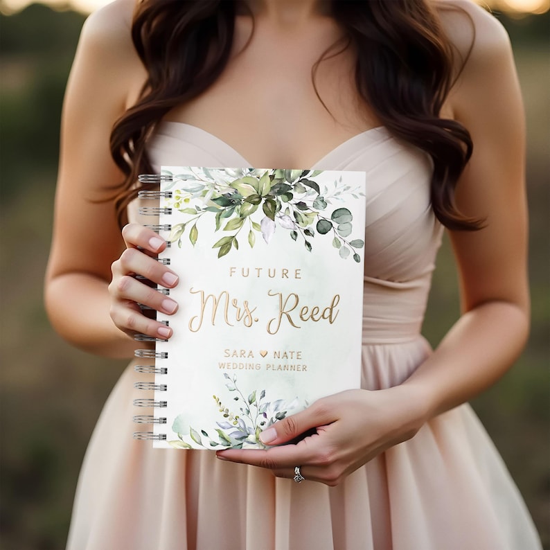 Personalized greenery wedding planner book with floral design and gold foil text. Features lush greenery artwork. Perfect for organizing wedding details, budgeting, and checklists. An ideal bridal shower gift, engagement present, or keepsake.
