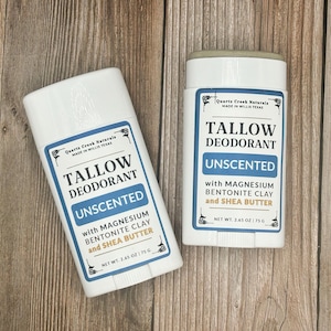 K&ouml;nnte beinhalten: Zwei wei&szlig;e Deodorant-Stifte aus Kunststoff mit blau-wei&szlig;en Etiketten. Der Text lautet Quartz Creek Naturals, Tallow Deodorant, Unscented, with Magnesium, Bentonite Clay and Shea Butter, Net Wt. 2.65 oz | 75 g. Die Beh&auml;lter haben einen Drehmechanismus.