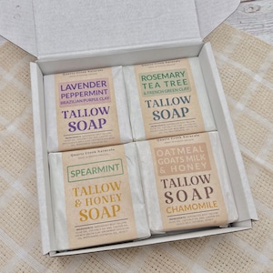 May include: A set of four natural tallow soap bars in a white box. The soaps are labeled with different scents: Lavender Peppermint, Rosemary Tea Tree, Spearmint & Honey, and Oatmeal Goats Milk & Honey.