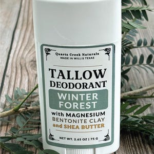 K&ouml;nnte beinhalten: Ein wei&szlig;er Deodorant-Stick aus Kunststoff mit einem Etikett, auf dem Quartz Creek Naturals, Tallow Deodorant, Winter Forest, mit Magnesium, Bentonit-Ton und Sheabutter, Nettogewicht 75 g steht. Das Etikett enth&auml;lt schwarzen und gr&uuml;nen Text.