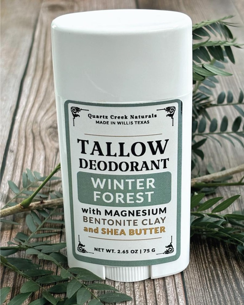 K&ouml;nnte beinhalten: Ein wei&szlig;er Deodorant-Stick aus Kunststoff mit einem Etikett, auf dem Quartz Creek Naturals, Tallow Deodorant, Winter Forest, mit Magnesium, Bentonit-Ton und Sheabutter, Nettogewicht 75 g steht. Das Etikett enth&auml;lt schwarzen und gr&uuml;nen Text.