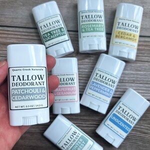 K&ouml;nnte beinhalten: Sieben wei&szlig;e Kunststoff-Deodorantstifte mit der Aufschrift Quartz Creek Naturals Tallow Deodorant in verschiedenen Duftrichtungen wie Patchouli & Cedarwood, Tea Tree & Eucalyptus, Rosemary & Tea Tree, Cedar & Bergamot, Grapefruit & Geranium, Lavender & Peppermint und Unscented.