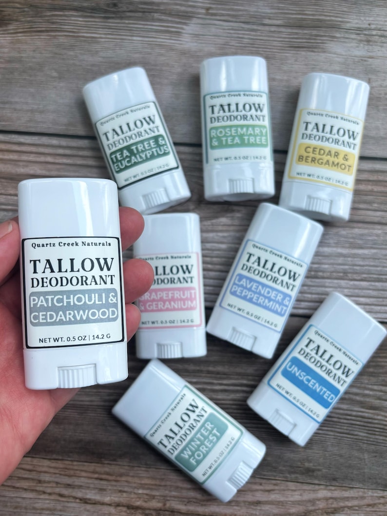 K&ouml;nnte beinhalten: Sieben wei&szlig;e Kunststoff-Deodorantstifte mit der Aufschrift Quartz Creek Naturals Tallow Deodorant in verschiedenen Duftrichtungen wie Patchouli & Cedarwood, Tea Tree & Eucalyptus, Rosemary & Tea Tree, Cedar & Bergamot, Grapefruit & Geranium, Lavender & Peppermint und Unscented.
