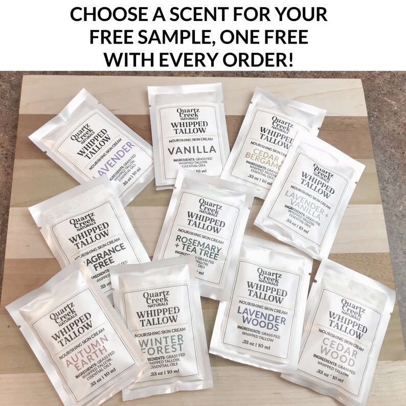 May include: A selection of small, silver, foil-wrapped packages of whipped tallow skin cream. Each package features a different scent, including Lavender + Vanilla, Cedarwood, Rosemary + Tea Tree, and Winter Forest. The packages are arranged on a wooden surface. Choose a scent for your free sample, one free with every order!