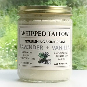 May include: A glass jar with a gold lid containing a white whipped cream. The label reads "Whipped Tallow Nourishing Skin Cream Lavender + Vanilla Made with: Whipped Grass Fed Tallow 16 oz | 473 ml Essential Oils: Lavender and Vanilla All Natural".